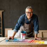 A person selecting paint color from swatches, with a paint can and brush nearby.